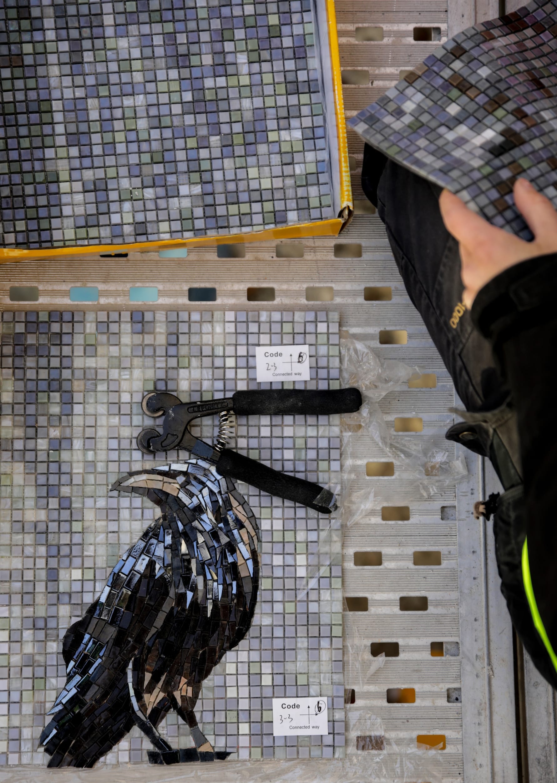 Mosaikplattor med motiv kråka, händer och verktyg